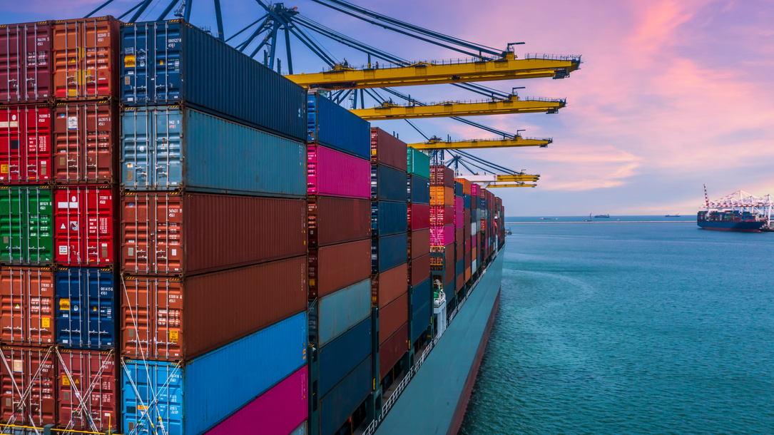 Freight vessel alongside container cranes at sunset